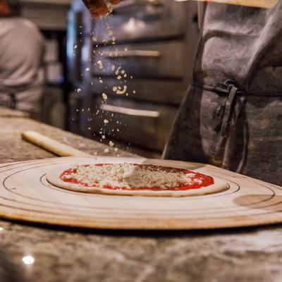 Chef sprinkling cheese on top of the pizza dough