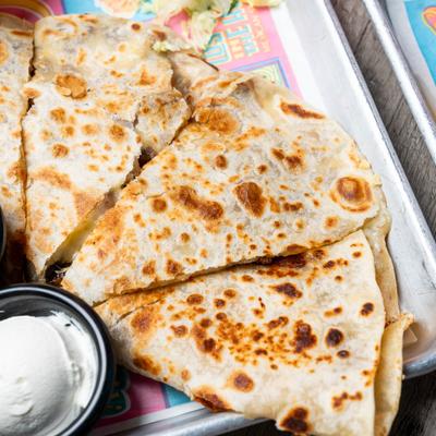 Cheese quesadilla served with a cup of sour cream.
