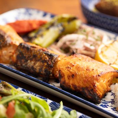 Salmon Kebab served with fresh and grilled vegetables, close-up.