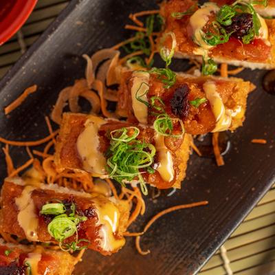 Sushi rolls topped with spicy sauce.