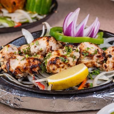 Grilled malai chicken served on a sizzling skillet with onions and lemon.