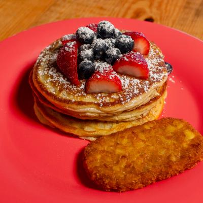 Pancakes with berries and strawberries, and a hashbrown.