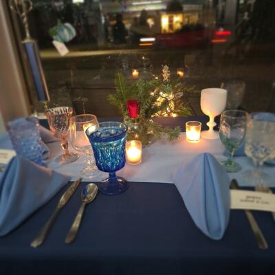 Elegant dinner setup with glassware, napkins, candles, and a floral centerpiece.