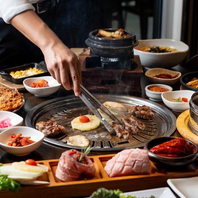 A hand grilling food in the middle of a full table.