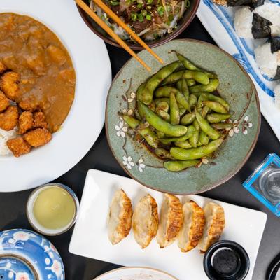A spread of various Japanese dishes including curry, dumplings, and edamame.