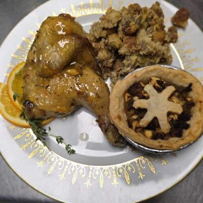 Roast chicken with stuffing and a mini pie, garnished with orange slices.