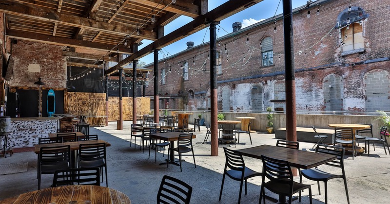 Exterior, industrial backyard seating area, partially covered, tables and chairs, lanterns