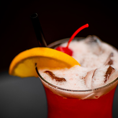Red cocktail with a chery and lemon decorations and a straw