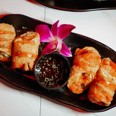 Portion of Egg Rolls served with a dipping sauce, top view.