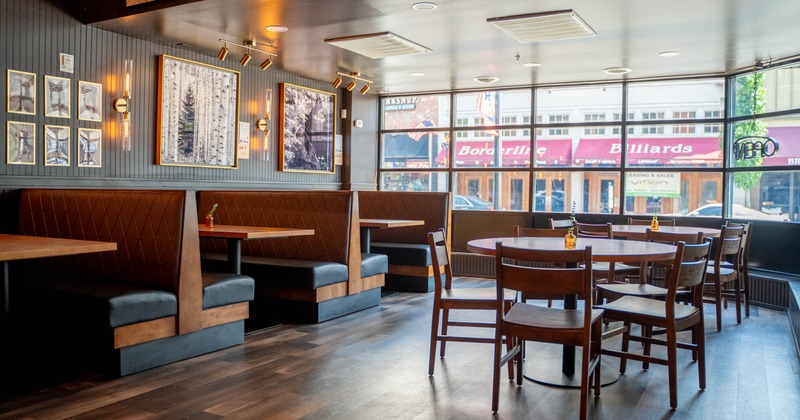 Interior booth seating, a round table, and large windows allowing natural light