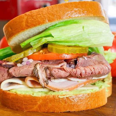 Roast beef sandwich with mushrooms, lettuce, tomato, and cheese.