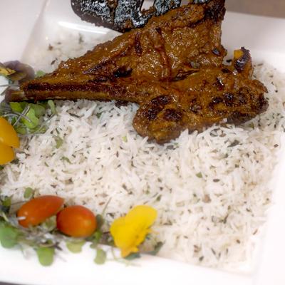 Grilled lamb chops served over a bed of white rice.