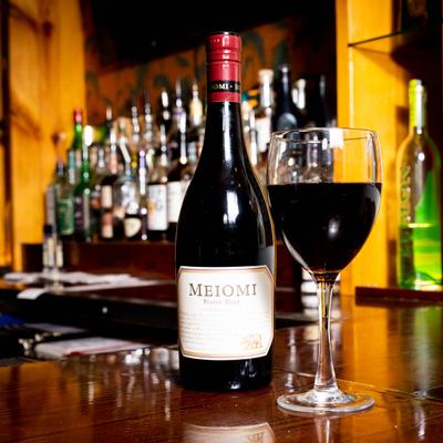 Red wine bottle and glass served on bar counter