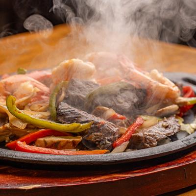 Steaming surf and turf fajitas served on a cast-iron skillet.