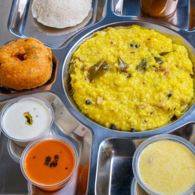 A platter with yellow lentil and rice dish and various sides.