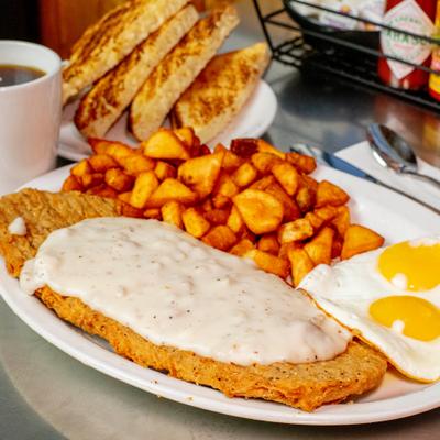 Chicken fried steak served with eggs, potatoes, toast.