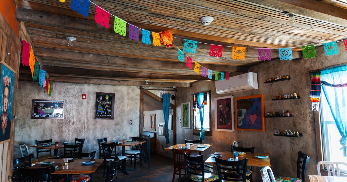 A vibrant restaurant interior with colorful papel picado banners, rustic wooden ceilings