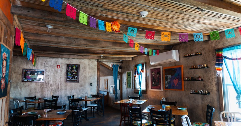 A vibrant restaurant interior with colorful papel picado banners, rustic wooden ceilings