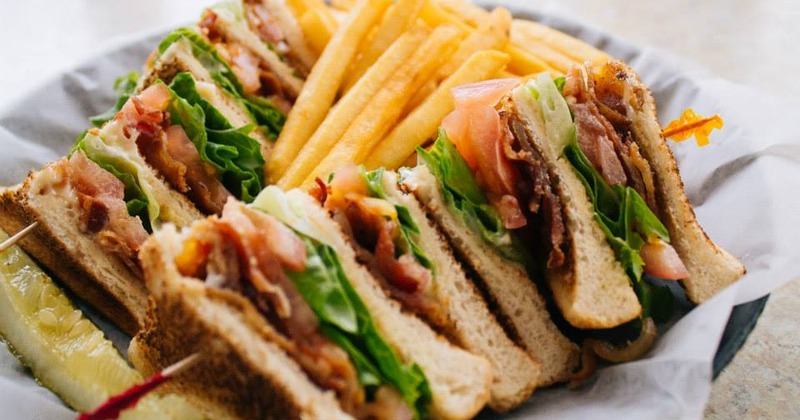 BLT Club sandwich served with fries on a white plate