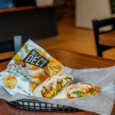 Grilled chicken wrap beside a bag of spicy potato chips.