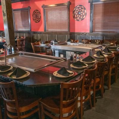 Interior featuring a large table set with plates and napkins surrounding two cooking grills.