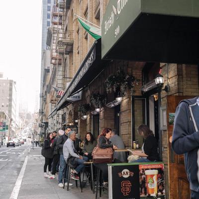 Street scene outside, with people sitting and chatting at outdoor tables.