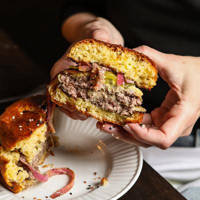 Hands holding a burger sliced in half, close-up.