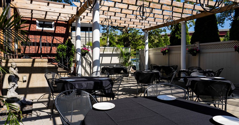 Outdoor patio with tables and chairs under a wooden pergola