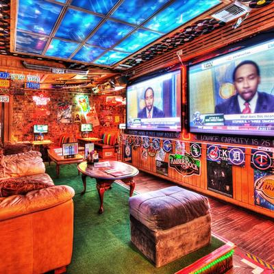 Cozy sports lounge with leather couches, large screens showing a sports debate, colorful decor