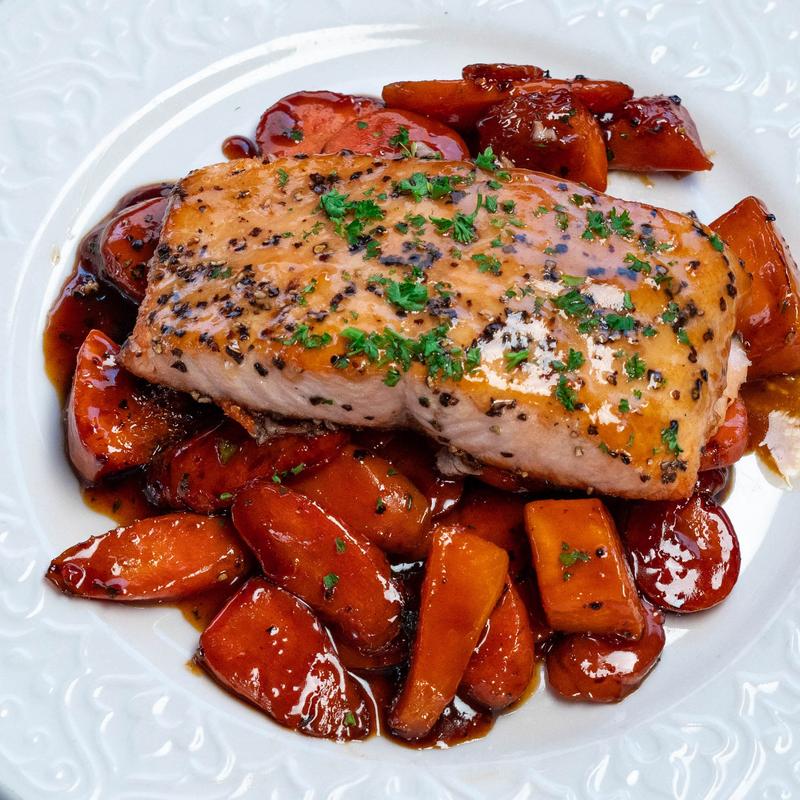 maple glazed salmon on vegetables on a white plate