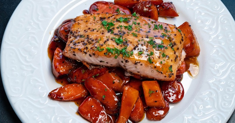 maple glazed salmon on vegetables on a white plate
