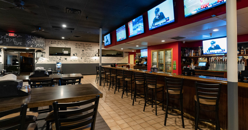 Interior, guest tables, bar, wall TVs above the bar