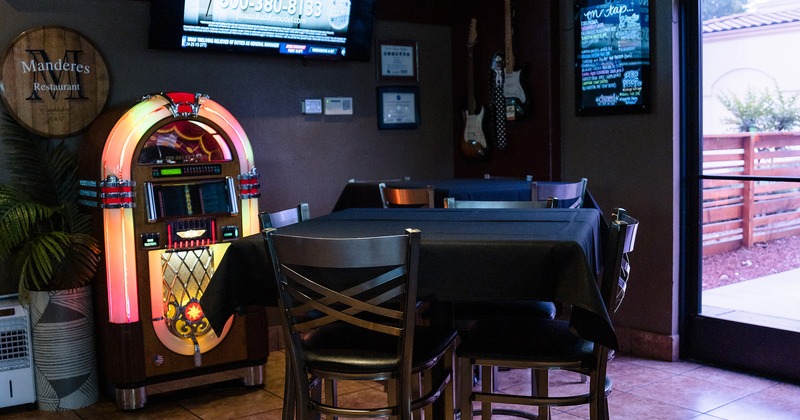 High tables with a black tablecloth and upholstered stools next to the  jukebox machine