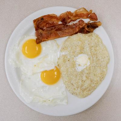 Breakfast plate with eggs bacon and grits.