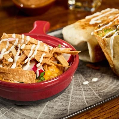 Tortilla soup topped with crispy strips and sauce, alongside Southwest Wrap.