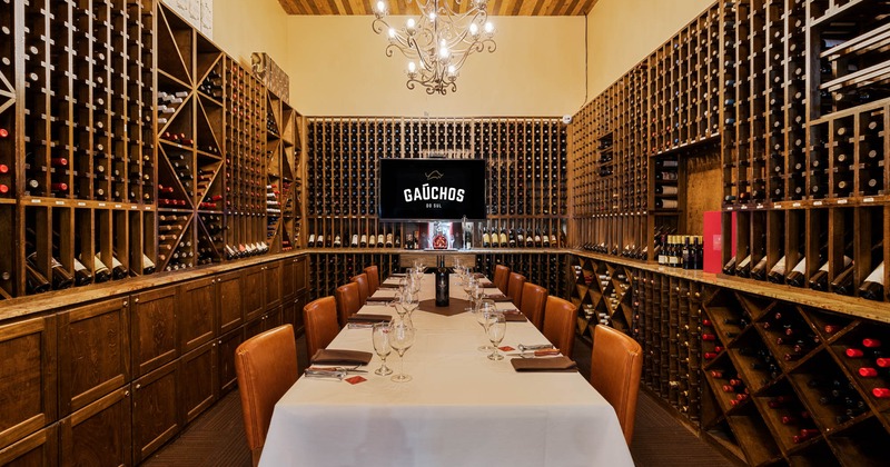 A large table ready for dining surrounded by wine racks