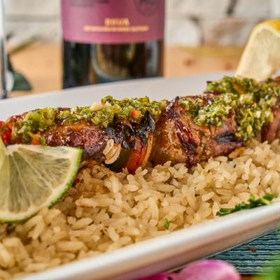 Colombian beef skewers with chimichurri sauce and rice.