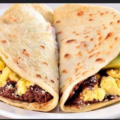 Two thick tortillas filled with beef, scrambled eggs and avocado.