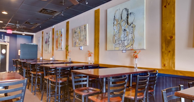 Interior, high seating tables with bar stools, fans on a ceiling, paintings on the wall