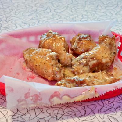 Parmesan Wings served in a red basket lined with paper.