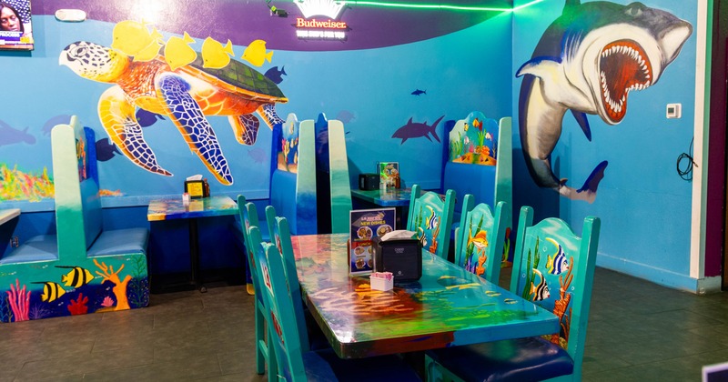 Restaurant interior with ocean-themed mural and booths