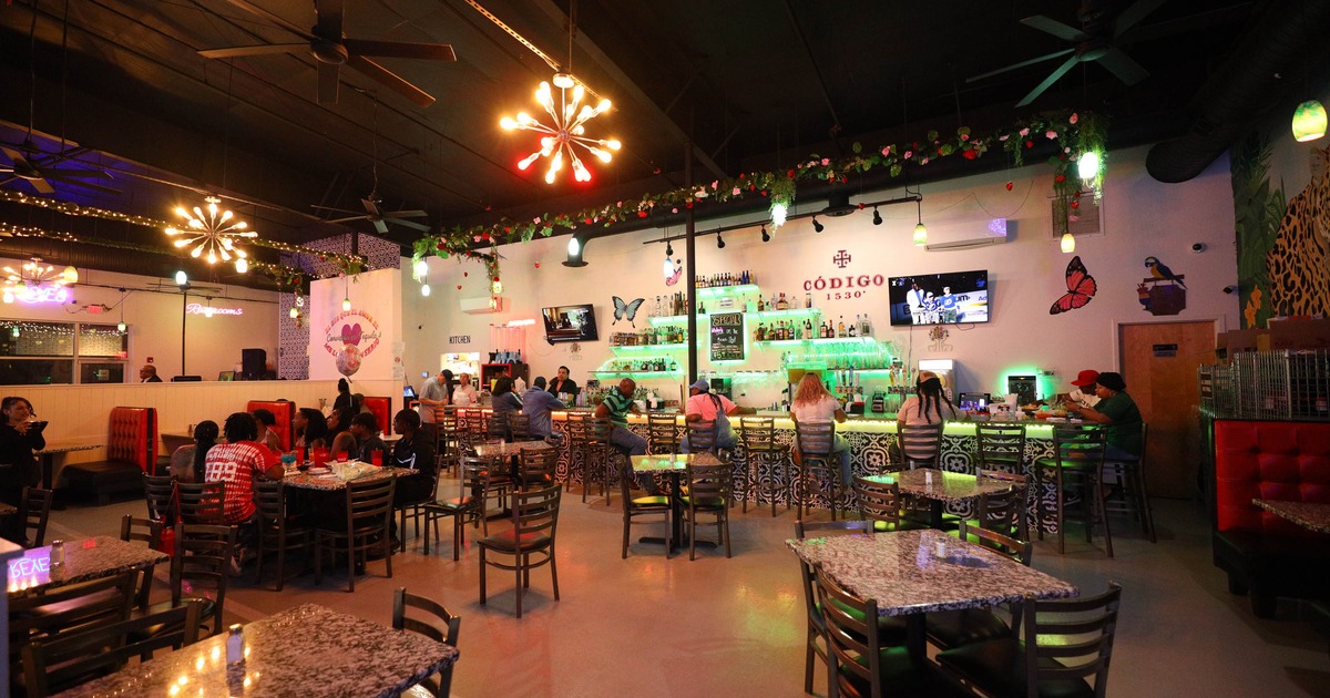 Lively restaurant interior with patrons at tables and a bar