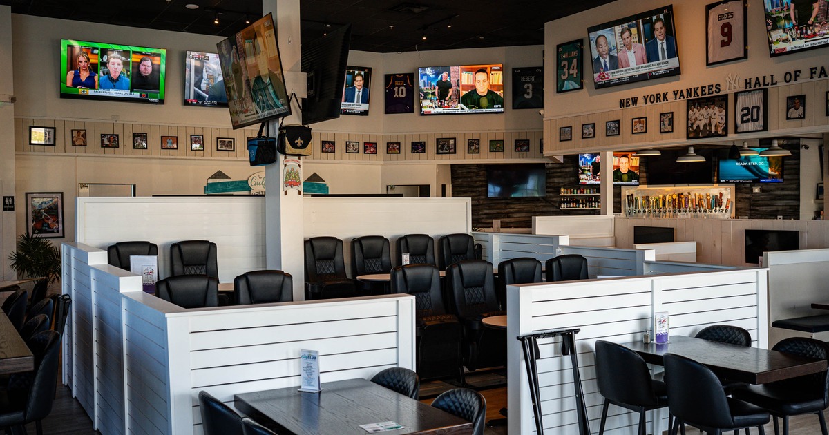 Interior of a sports bar with partitioned seating, multiple TVs displaying sports