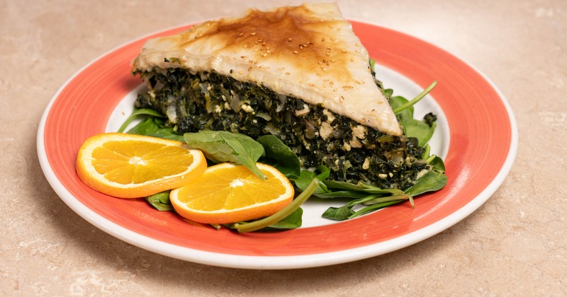 Spinach and cheese pie with orange slices and spinach leaves on the plate