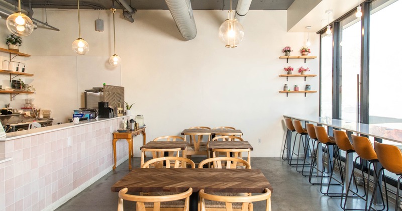 Modern cafe interior with wooden furniture, pendant lighting, and large windows