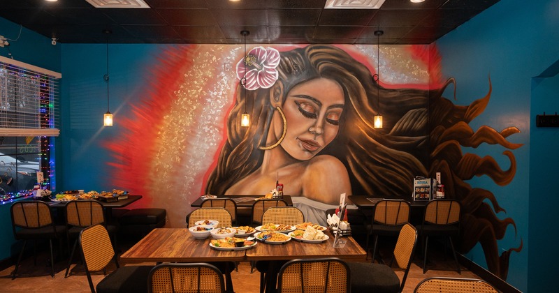 Interior dining area with a large mural of a woman on the wall