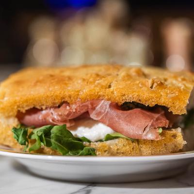 Sandwich with prosciutto, mozzarella, and arugula.