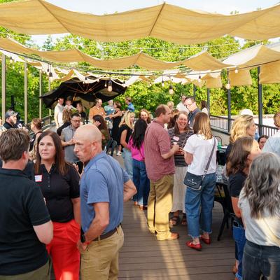 People socializing on rooftop patio under fabric canopies and lights.