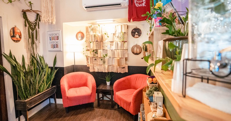 A cozy room corner with red armchairs, eclectic decor, and a small table with a plant