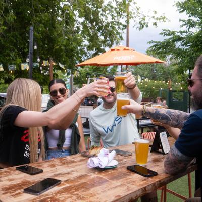 People cheering with glasses of beer at the outdoor table.